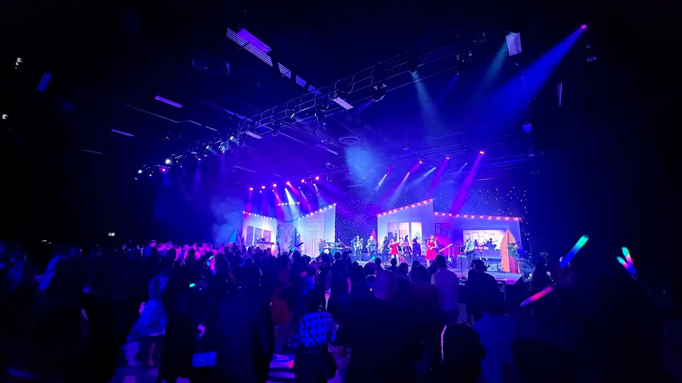A packed room of guests waving glowsticks in front of the uRequest Live stage